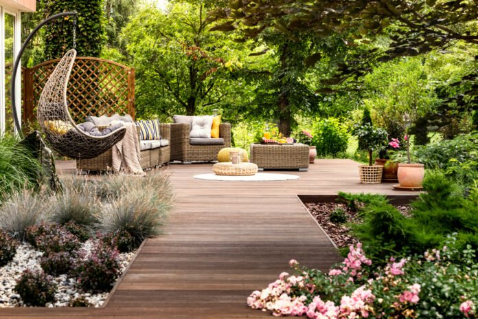 Duurzame tuinmeubelen op een groen gazon, bestaande uit een FSC-gecertificeerde houten tafel en stoelen, omgeven door kleurrijke bloemen en planten, weerspiegelend een milieuvriendelijke en stijlvolle buitenleefruimte